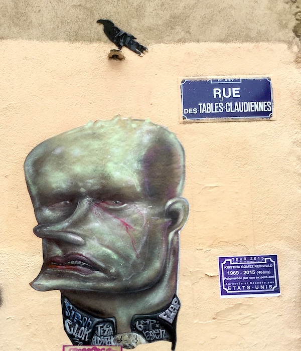 Œuvre de Flap, rue des Tables Claudiennes, photographie du 1er décembre 2015 — Au-dessus, perché sur une pierre dépassant du mur, un oiseau de Keza — On remarque à droite une plaque de la Journée du Souvenir Trans (TDOR ) des victimes de transphobie, ici Kristina Gomez Reinwald, assassinée aux États-Unis.